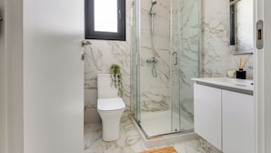 Un bagno moderno con doccia vetrata, un water e un lavabo con specchio.