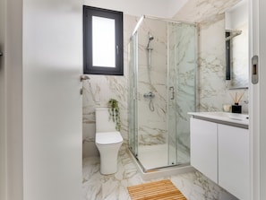 A modern bathroom with a glass-enclosed shower, a toilet, and a vanity with a mirror. - Sanders Triple Limassol (Limassol)
