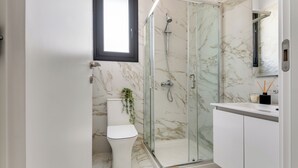 Un bagno moderno con doccia vetrata, un water e un lavabo con specchio.