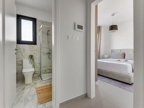 A modern bathroom with a glass shower enclosure, a toilet, and a marble floor. - Sanders Triple Limassol (Limassol)