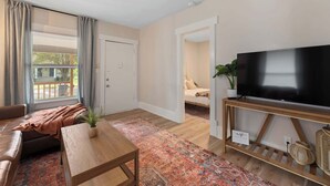 A living room with a sofa, coffee table, TV, and a patterned rug.