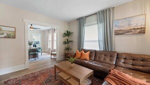 A living room with a brown leather sofa, a wooden coffee table, and a patterned rug.