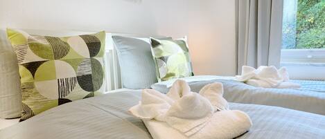 A hotel room with two beds, each with a pillow and a towel.