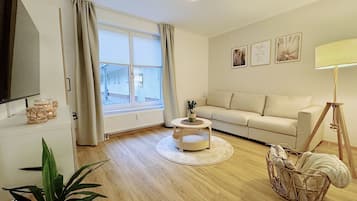 Un salon avec un canapé, une table basse, un téléviseur et une lampe.