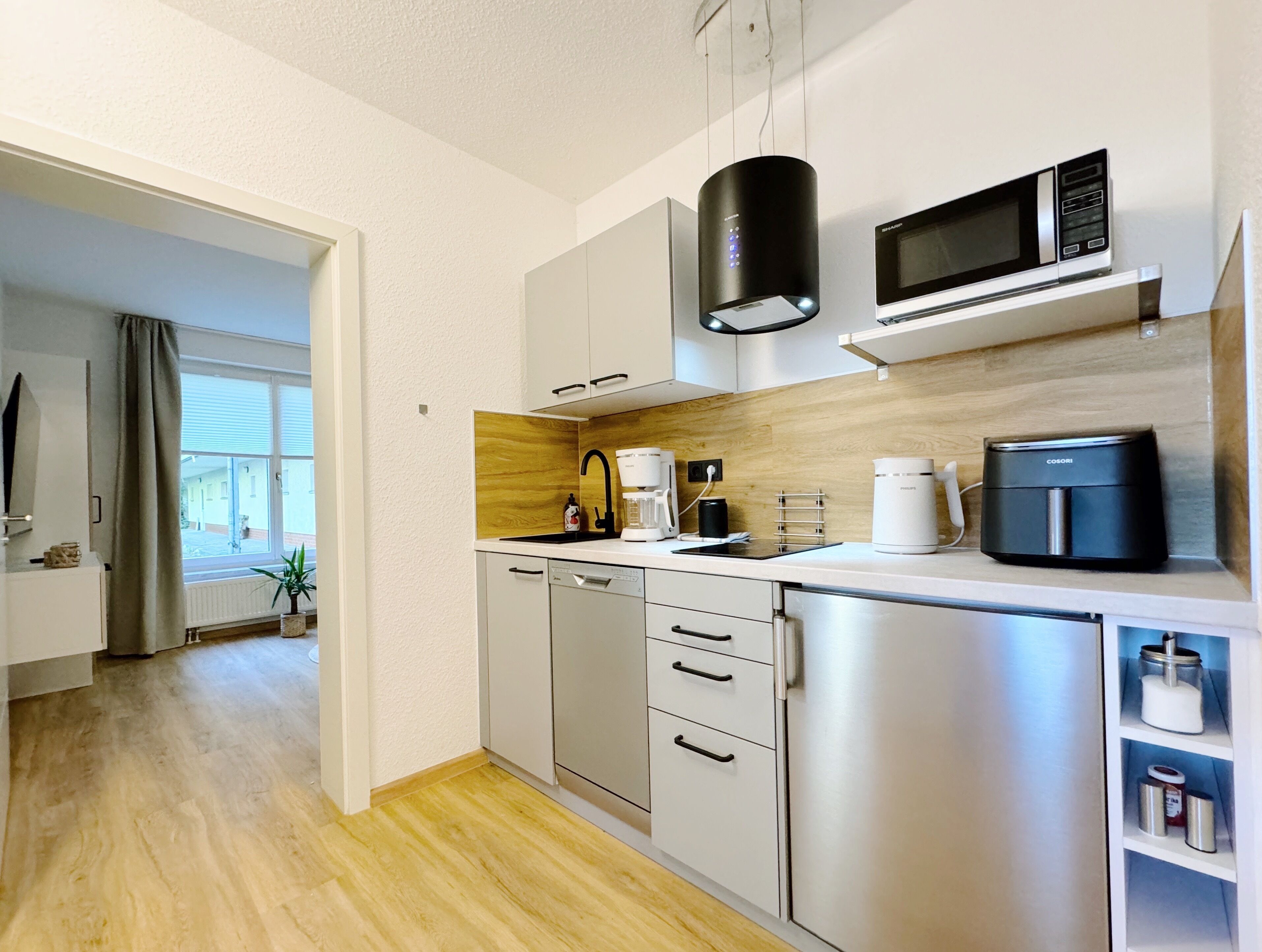 Una cucina moderna con elettrodomestici in acciaio inossidabile, una schiena di piano in legno e vista sull'esterno.