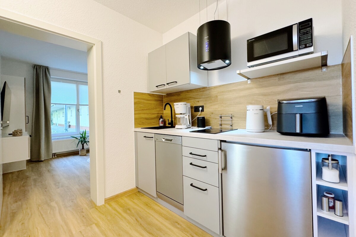 A modern kitchen with stainless steel appliances, a wooden backsplash, and a view to the outside.