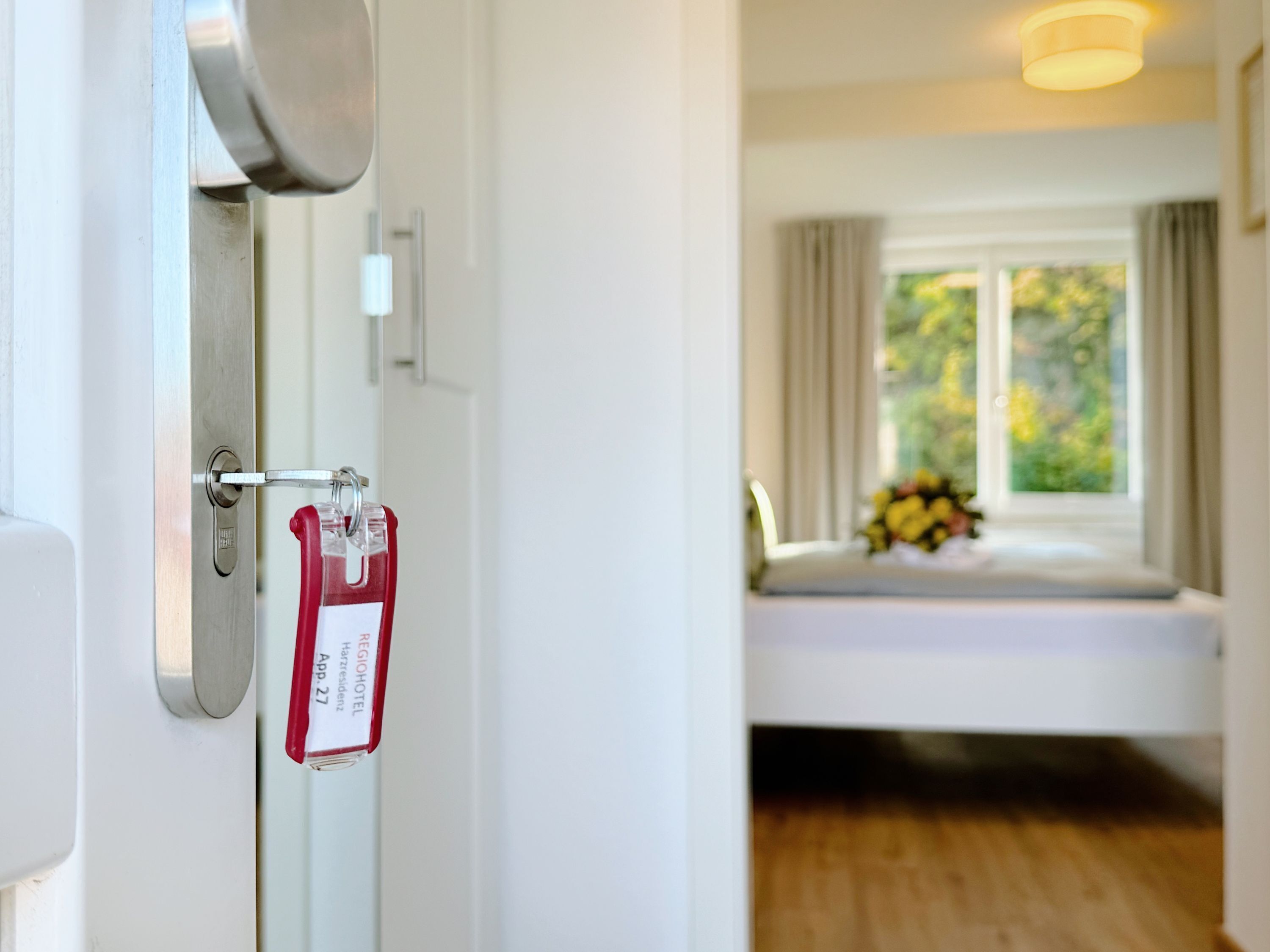 Une chambre d’hôtel avec un lit, une fenêtre avec des rideaux et une vue sur la verdure.