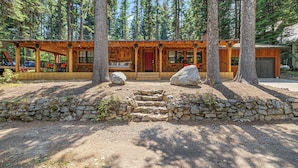 A rustic cabin with a stone foundation, wooden exterior, and a porch with seating. - Rustic Retreat - Near downtown, lake parks & hospital - Hot tub - 5 bd (McCall)
