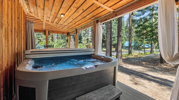 A hot tub under a wooden pergola with a view of trees. - Rustic Retreat - Near downtown, lake parks & hospital - Hot tub - 5 bd (McCall)