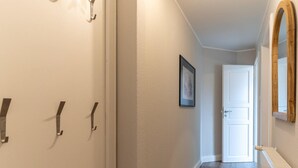En gang med en hvid dør, et billede i ramme på væggen og en radiator.
