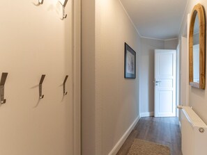 A hallway with a white door, a framed picture on the wall, and a radiator. - Ferienwohnung Lieblingsmeer (St. Peter-Ording)