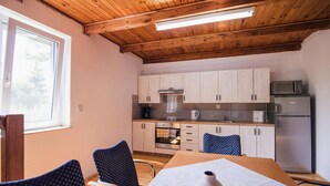 Una cocina funcional con armarios de madera, un microondas y un refrigerador. Hay una mesa de comedor con sillas y un florero sobre la mesa.