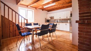 Una cocina moderna con armarios blancos, extractor de acero inoxidable y techo de madera.