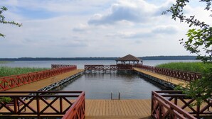 Un muelle de madera con barandillas rojas que lleva a un pabellón sobre el agua.