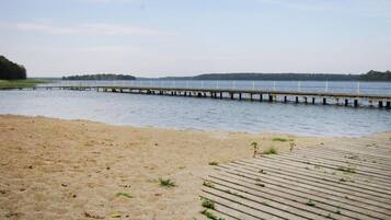 A sandy beach with a wooden pier extending into calm water.