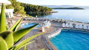 Ένας χώρος πισίνας με ξαπλώστρες και θέα σε μια λίμνη.