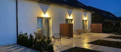 A modern house with a patio area, outdoor seating, and a well-lit entrance.