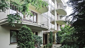 Un edificio de varios pisos con balcones, rodeado de vegetación.