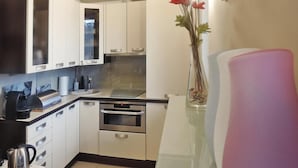 Una cocina moderna con armarios blancos, un horno de acero inoxidable y una cafetera.