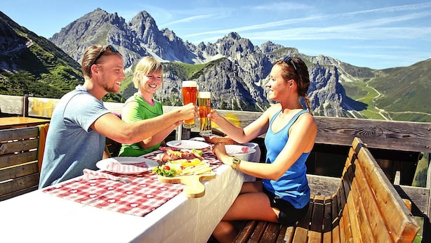 Een tafel met een geruit tafelkleed, borden met eten en glazen bier.