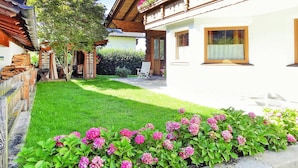 Een traditionele chalet met een verzorgde tuin, houten omheining en vrij uitzicht op de omgeving.