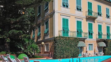 Un hotel con zona de piscina, mobiliario exterior y un jardín bien cuidado.