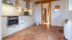 A modern kitchen with white cabinets, a built-in oven, and a coffee machine. - Ferienhaus in Westerhever mit Garten (Westerhever)