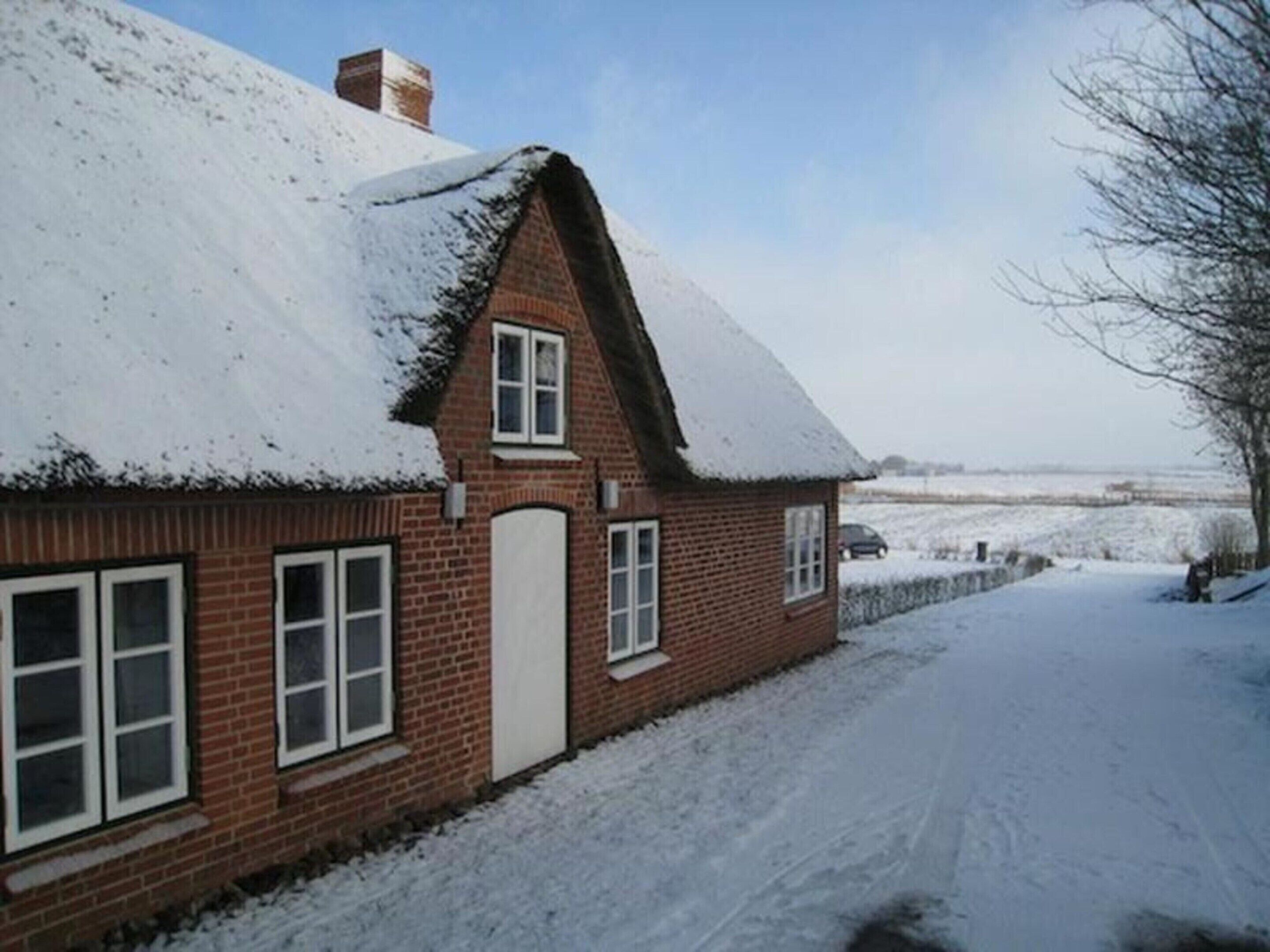 A brick house with a snow-covered roof and a clear sky.