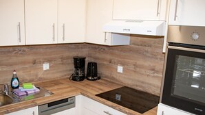 A modern kitchen with white cabinets, a wooden countertop, a built-in oven, and a coffee maker. - Nice Apartment in Breitenbrunn With Sauna (Breitenbrunn/Erzgeb.)