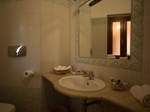 Un baño con lavamanos, espejo e inodoro.
