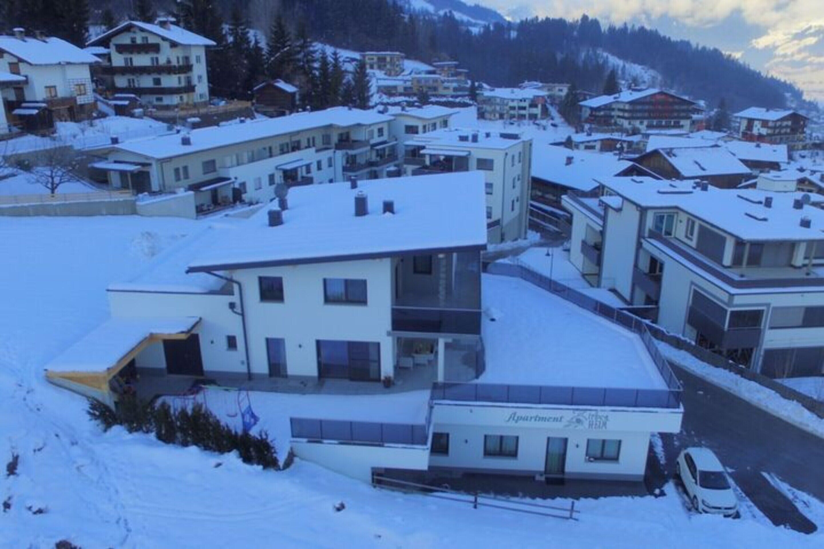Zona residencial con edificios modernos, un complejo de apartamentos visible y un paisaje cubierto de nieve.