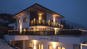 Un edificio moderno a due piani con balconi decorati da luci a stringa, con la scritta "Apartment Zirben Heim".