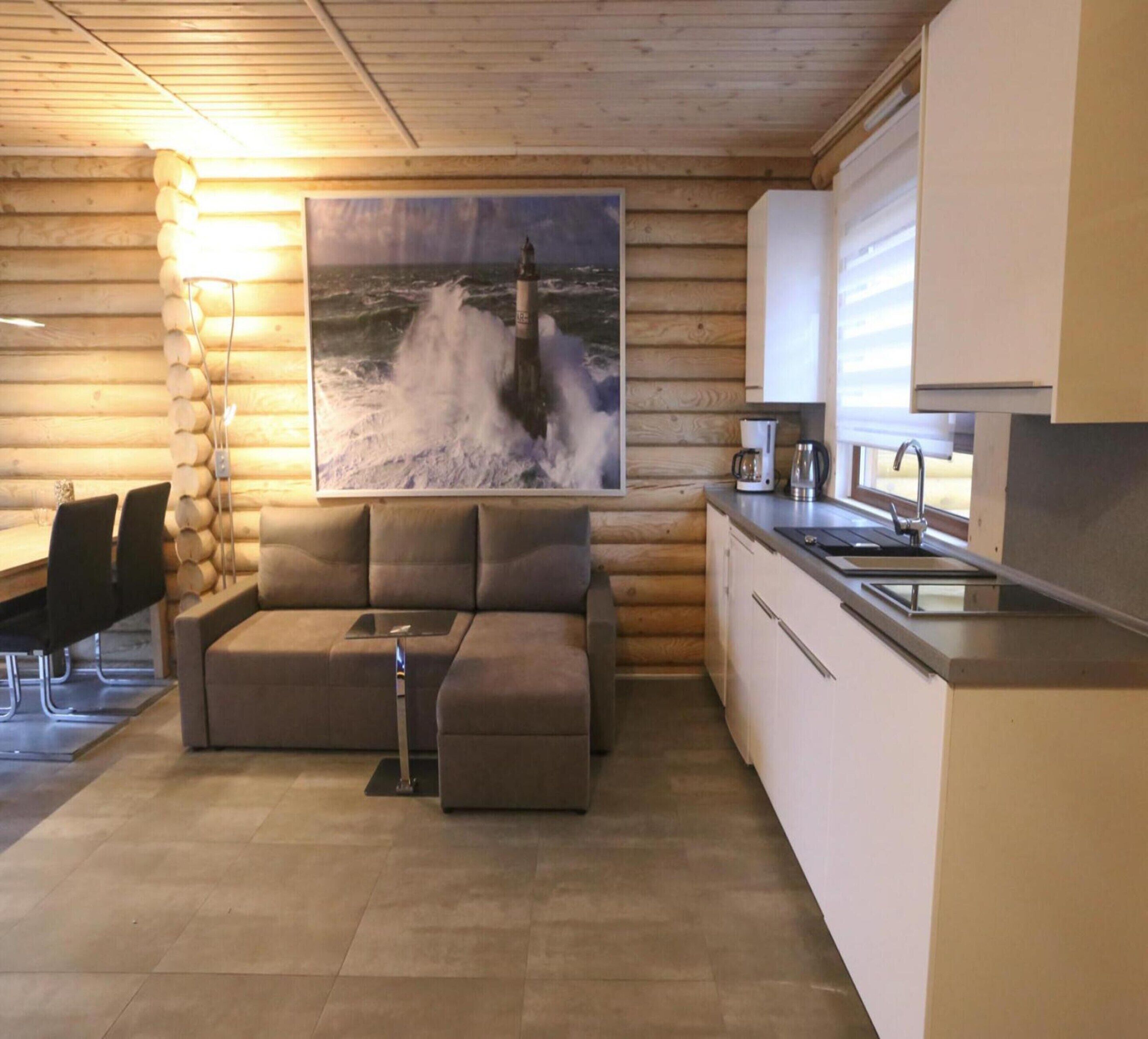 A cozy log cabin interior with a sofa, a dining area, and a kitchen.