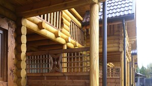 Eine Holzhütte mit verdeckter Veranda, einem Holztisch und einer Bank.