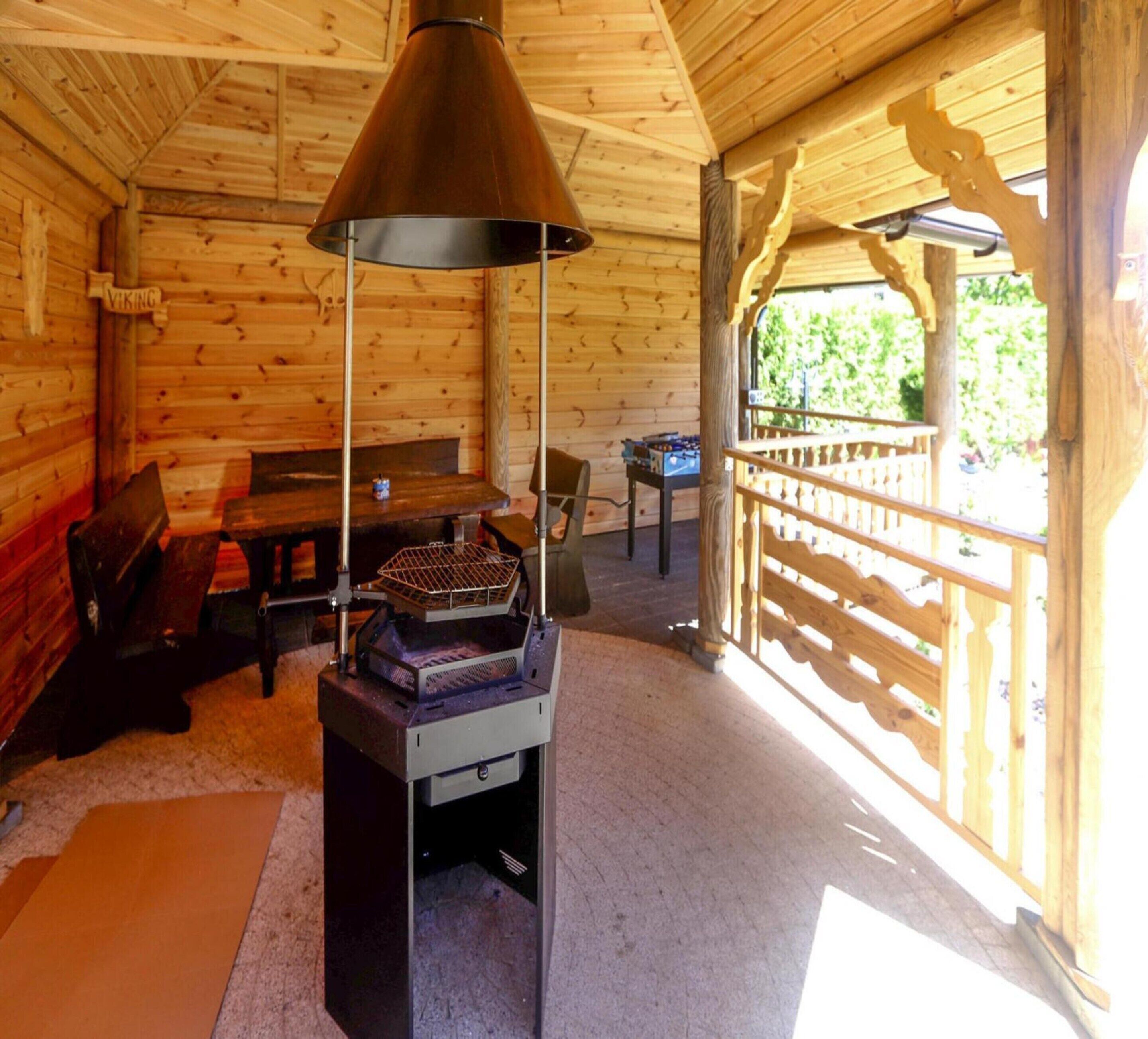 A wooden cabin interior with a table, benches, and a grill.