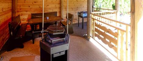 A wooden cabin interior with a table, benches, and a grill.