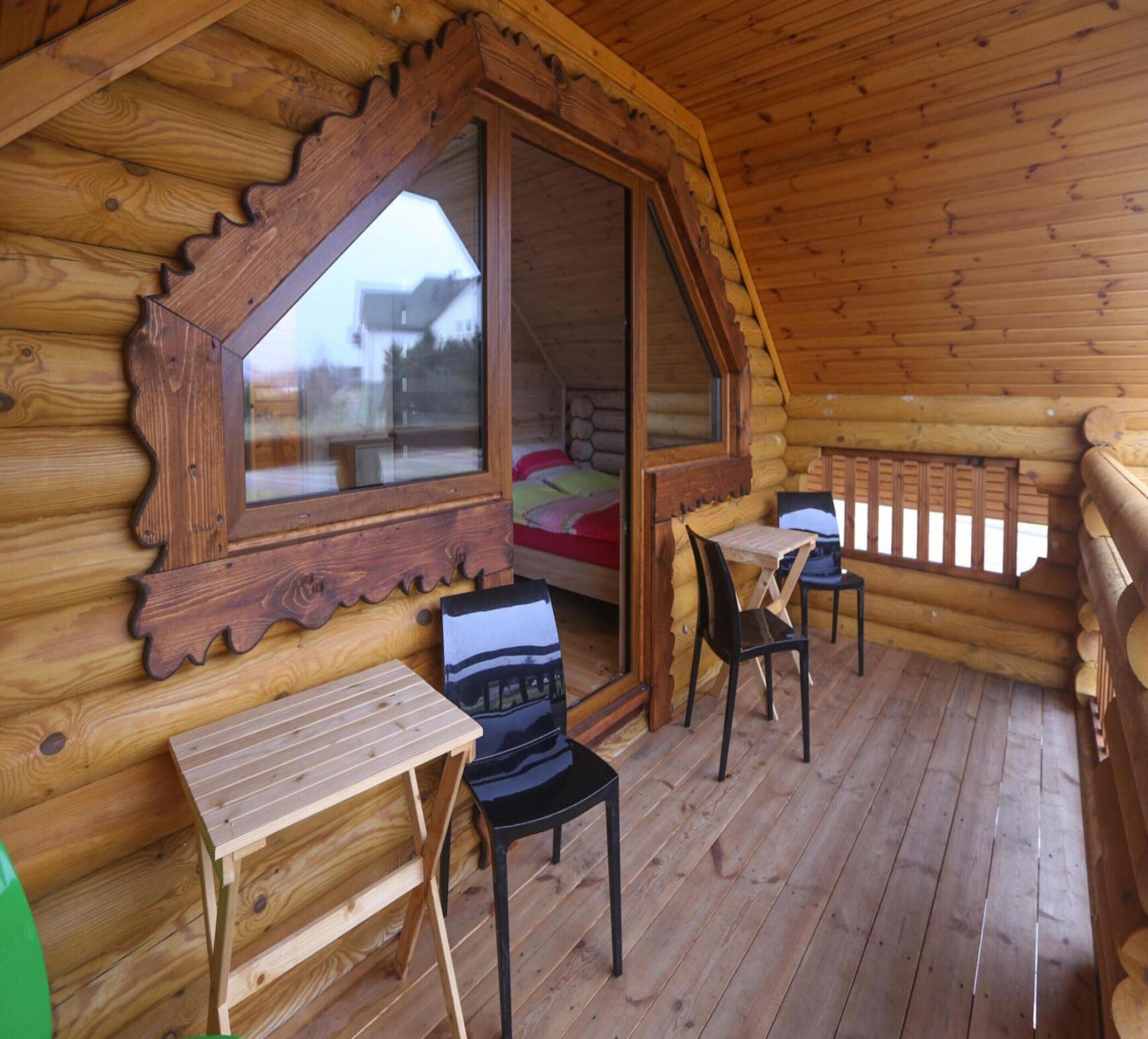 A cozy cabin with a wooden interior, a large window, a small table, and two chairs.