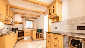 A kitchen with wooden cabinets, a built-in oven, and a window with curtains. - Holiday Home in Strass With Mountain Views (Strass im Zillertal)