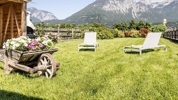 A wooden cabin with a garden in front, two white lounge chairs, and a mountain view. - Holiday Home in Strass With Mountain Views (Strass im Zillertal)
