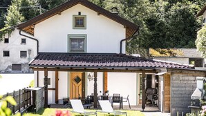 A two-story house with a covered patio, a wooden door, and a grill area. - Holiday Home in Strass With Mountain Views (Strass im Zillertal)