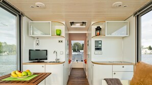 Un interior compacto y moderno con kitchenette, zona de estar y vista al agua.