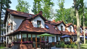 En række traditionelle huse i europæisk stil med saddeltage, store vinduer og udendørs siddepladser.