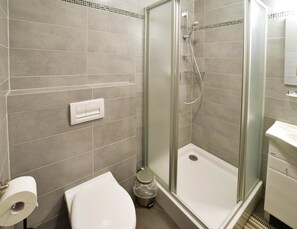 Kylpyhuone, jossa on wc, suihkukaappi ja pesuallas.