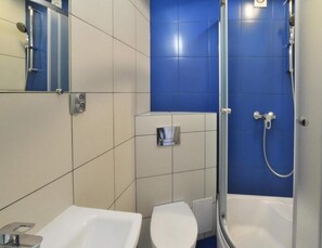 Ein Badezimmer mit Dusche, zwei Waschbecken und Toilette.