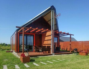 Ein modernes Haus mit Satteldach, großen Fenstern und einer überdachten Terrasse.