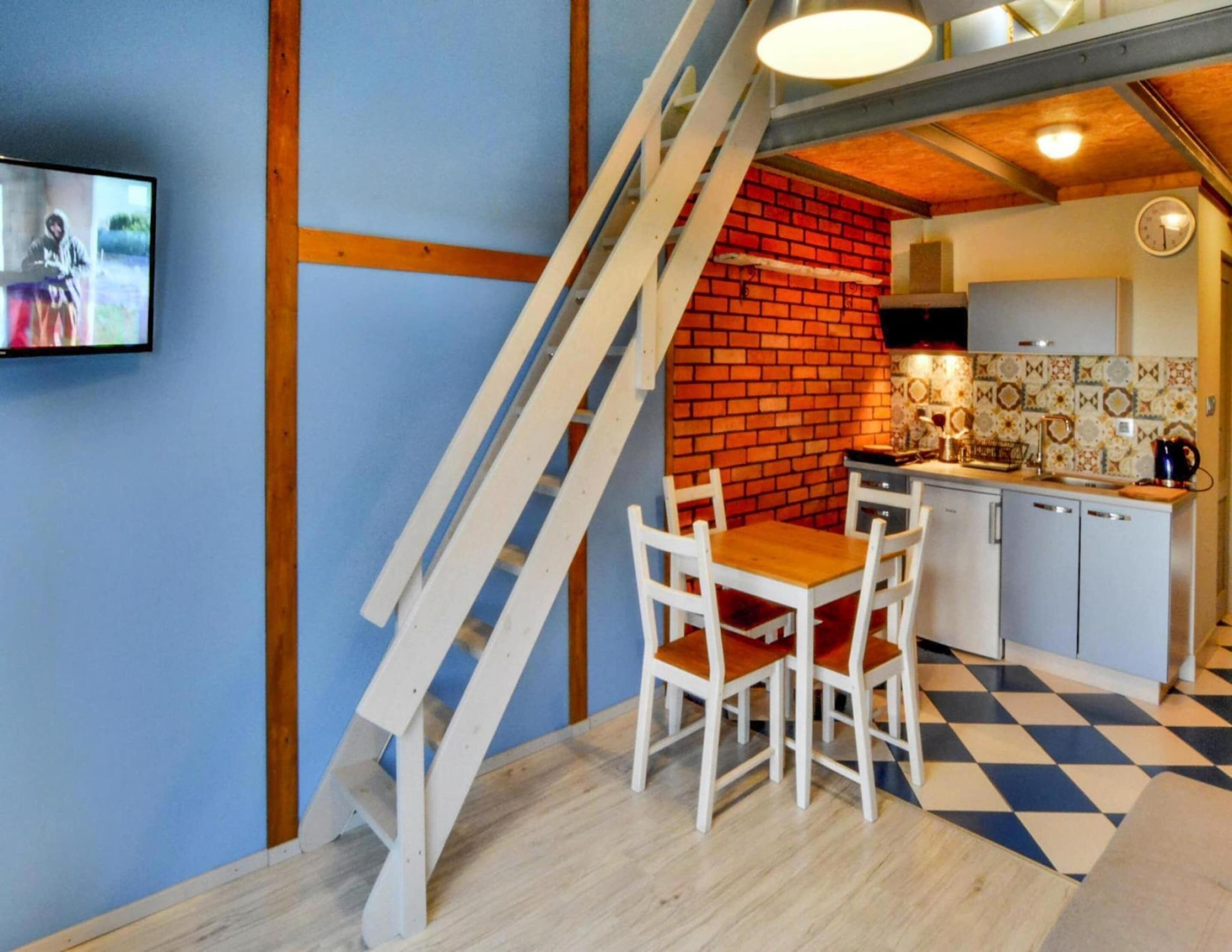 A kitchen with a red brick wall, white cabinets, and a checkered floor.