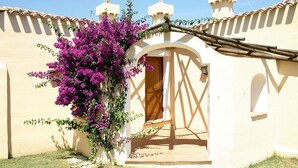 Un bâtiment à la façade beige, avec une porte en bois et un balcon orné de fleurs violettes.