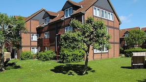 A two-story brick apartment building with multiple windows and a sloped roof. - Appartementhaus auf Pellworm (Pellworm)