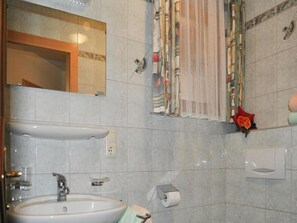 A bathroom with a sink, mirror, towel, toilet paper, and a shower curtain. - Apartments Home Val Sinestra, Kappl (Kappl)