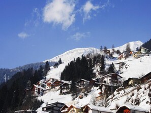 A snow-covered mountain village with traditional wooden houses, a clear blue sky, and a prominent snow-capped peak in the background. - Apartments Home Val Sinestra, Kappl (Kappl)